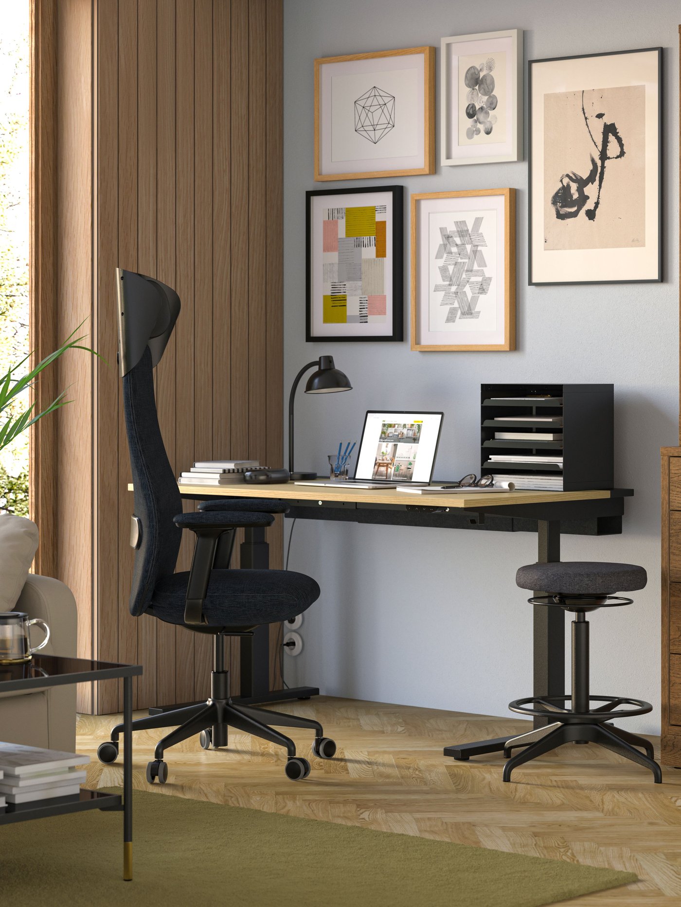 A workspace featuring a MITTZON sit/stand desk with a wooden tabletop and black legs, paired with a black GRÖNFJÄLL office chair and a black HARVMATTA desk organizer.