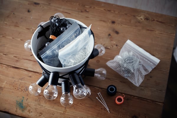 Hier sieht man einen Abfalleimer verziert mit einer Lichterkette und Sachen darin.