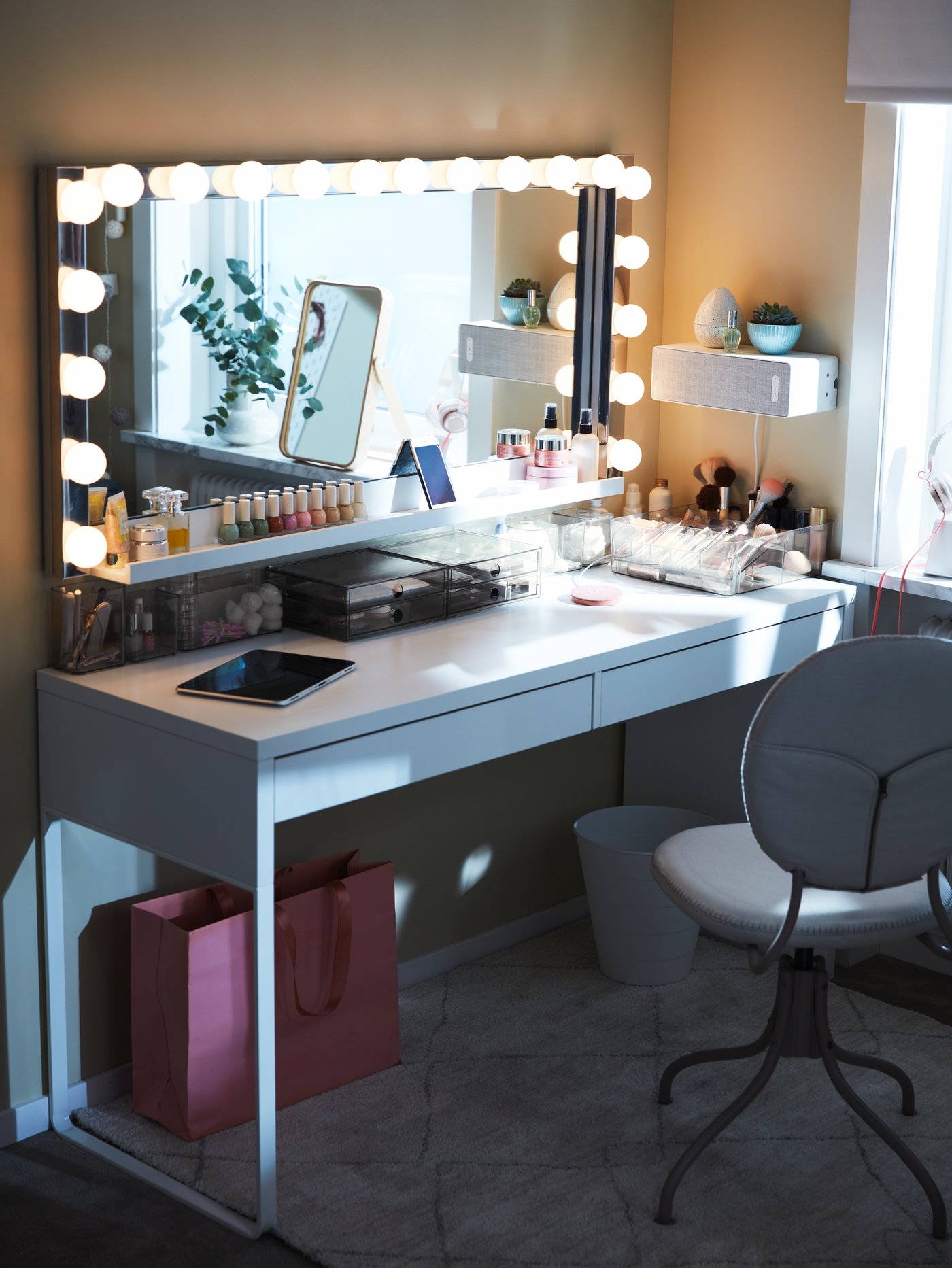 A vanity table made with a white MICKE desk with two drawers, a LÄRBRO mirror and LEDSJÖ wall lamps.