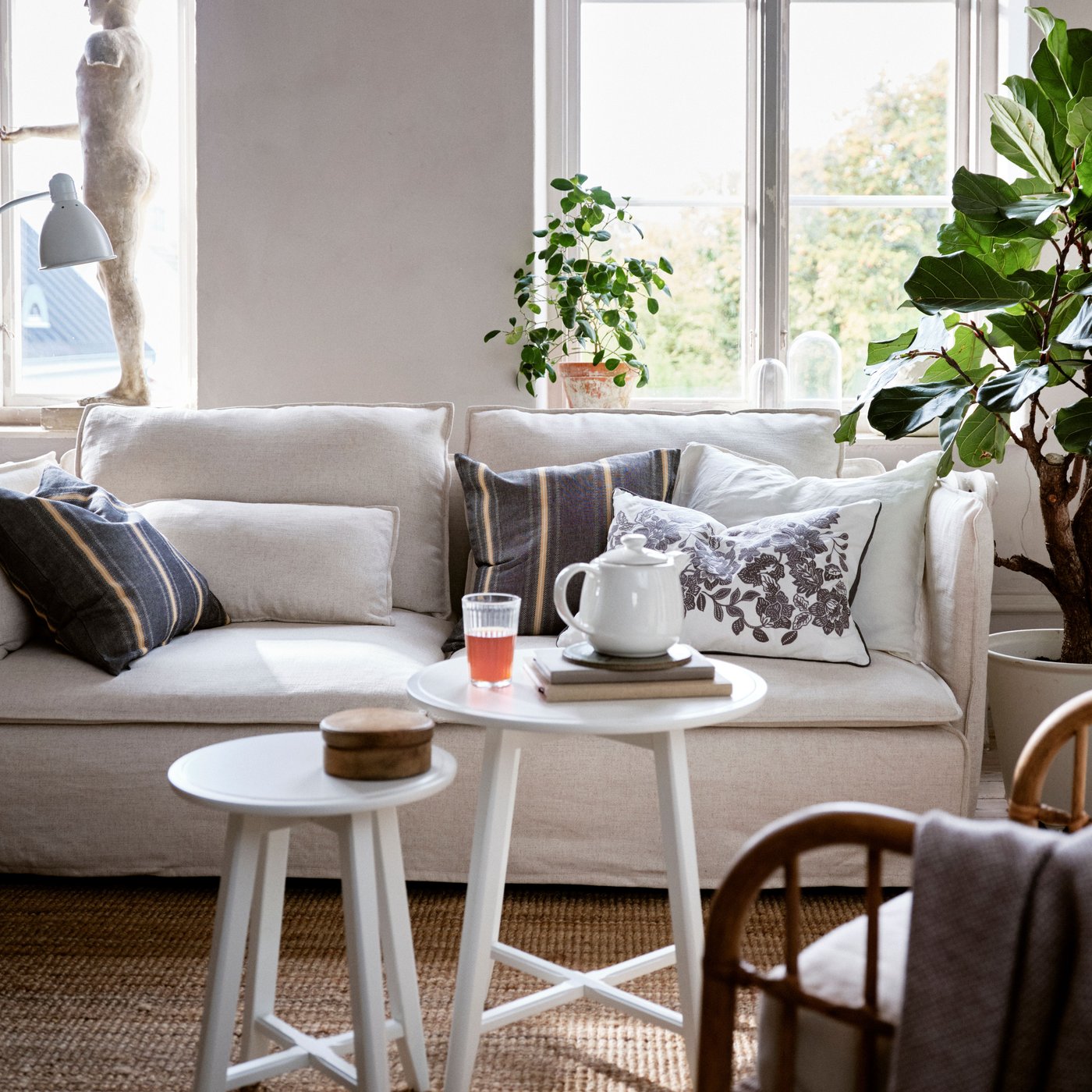 Wohnzimmer mit einem SÖDERHAMN Sofa, auf dem verschiedene Kissen liegen - eines davon ein SKUGGNÄVA Kissen mit Blumenmuster.