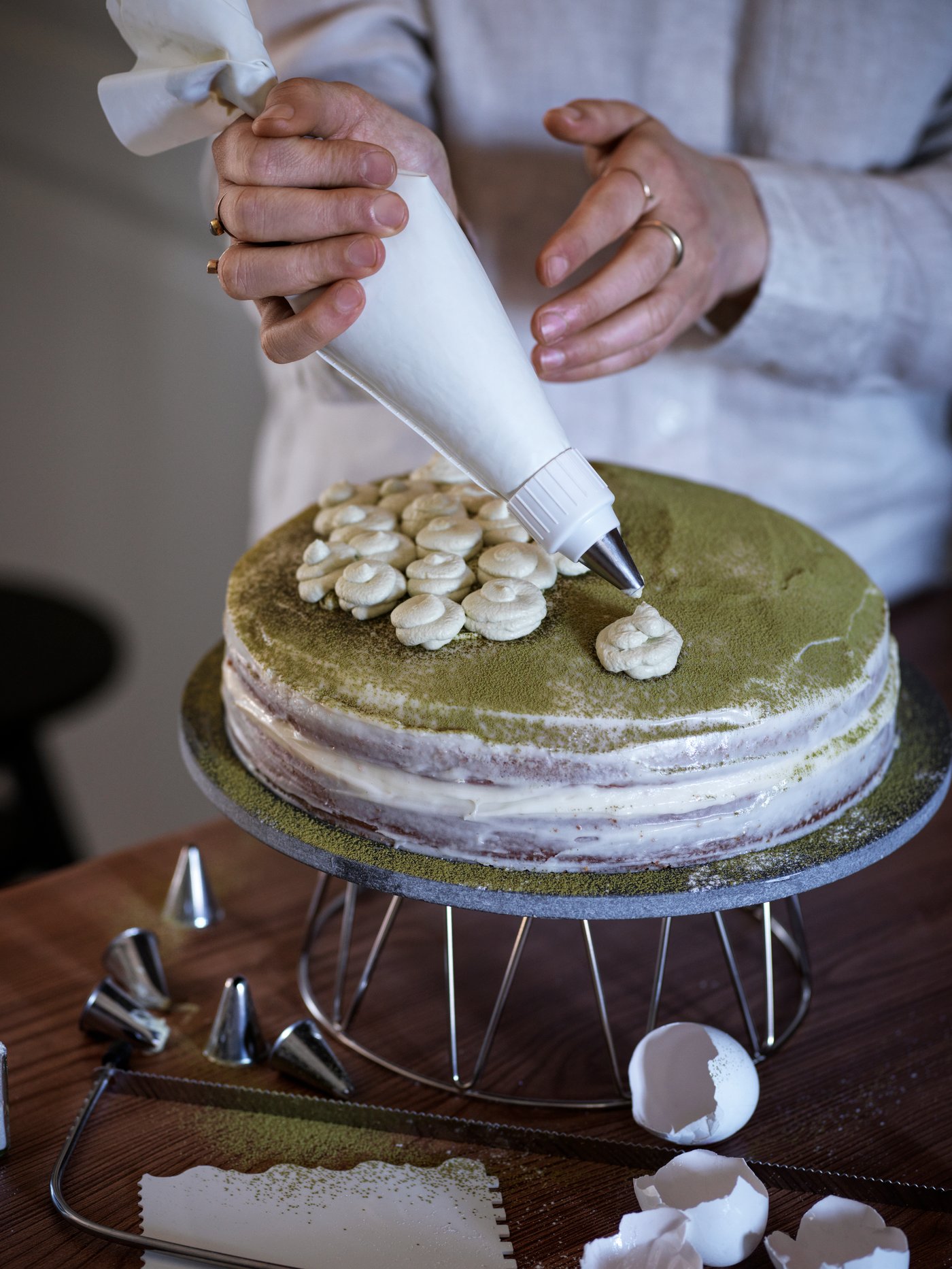 Eine Person dekoriert mit einem Spritzbeutel aus dem SMAKSAM Tortengarnierset eine Torte.