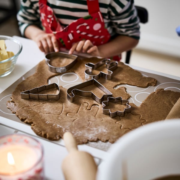 A child is using VINTERFINT pastry cutters to make festive cookie shapes from a gingerbread dough.