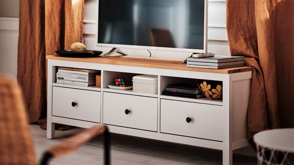 A white HEMNES TV bench with a wooden worktop and a TV in the living room.