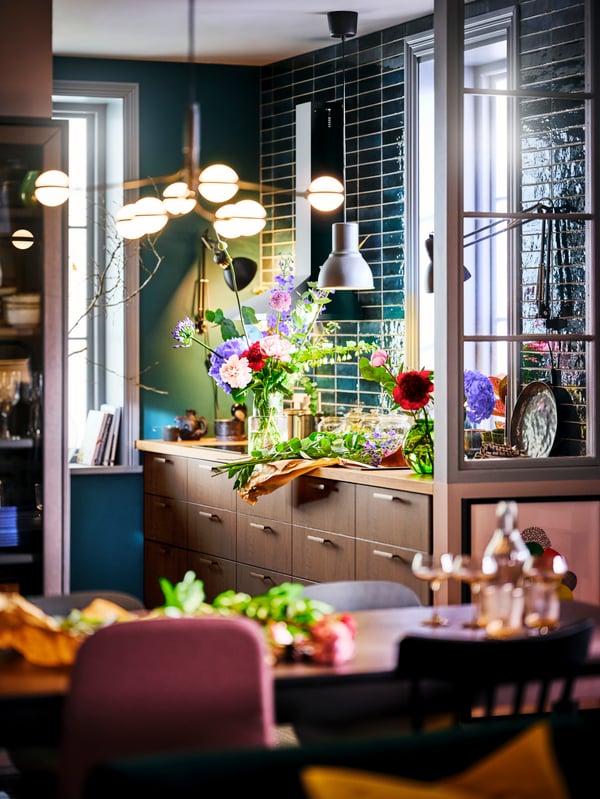 A STORSLINGA LED 8-armed chandelier illuminating a dining area with a SINARP kitchen in the background.