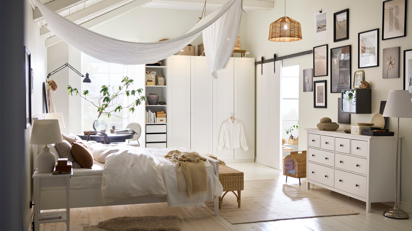 Lit HEMNES blanc avec linge de lit DYTÅG blanc, coussins bruns et rideau DYTÅG couvrant le plafond.