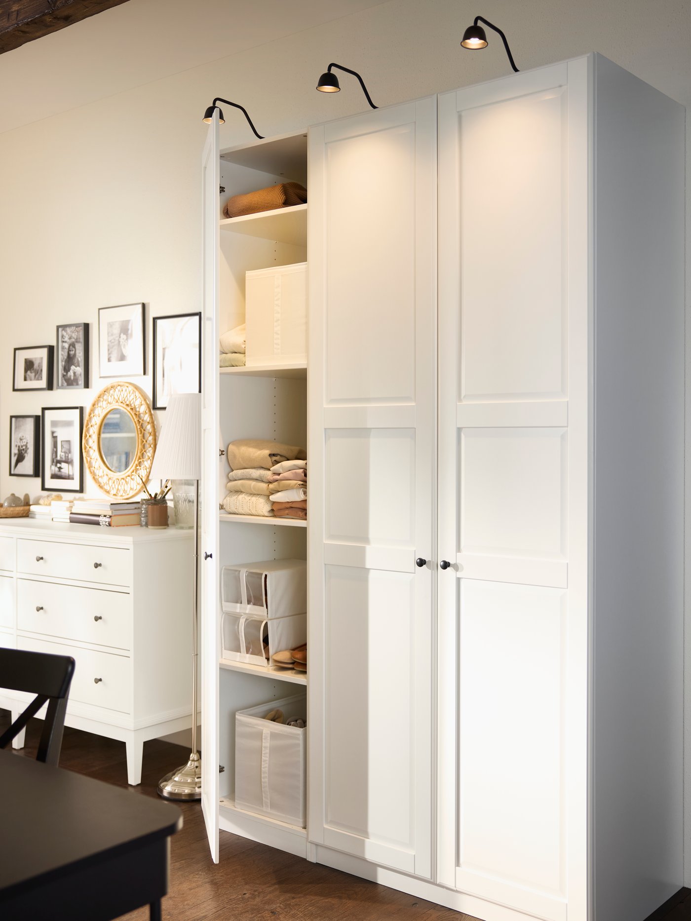Combination of PAX/TYSSEDAL wardrobes in white with one door open and IDANÄS chest of drawers in background.