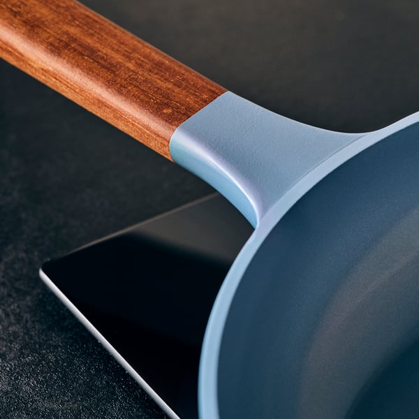 A KLIPPFISK frying pan with a wooden handle, sitting on a black stovetop.