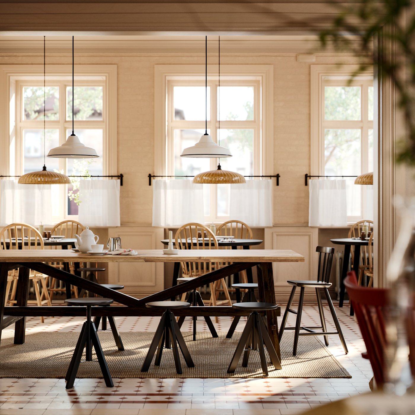 An acacia SKOGSTA dining table with black legs has height-adjustable black stools around it in a commercial dining area.