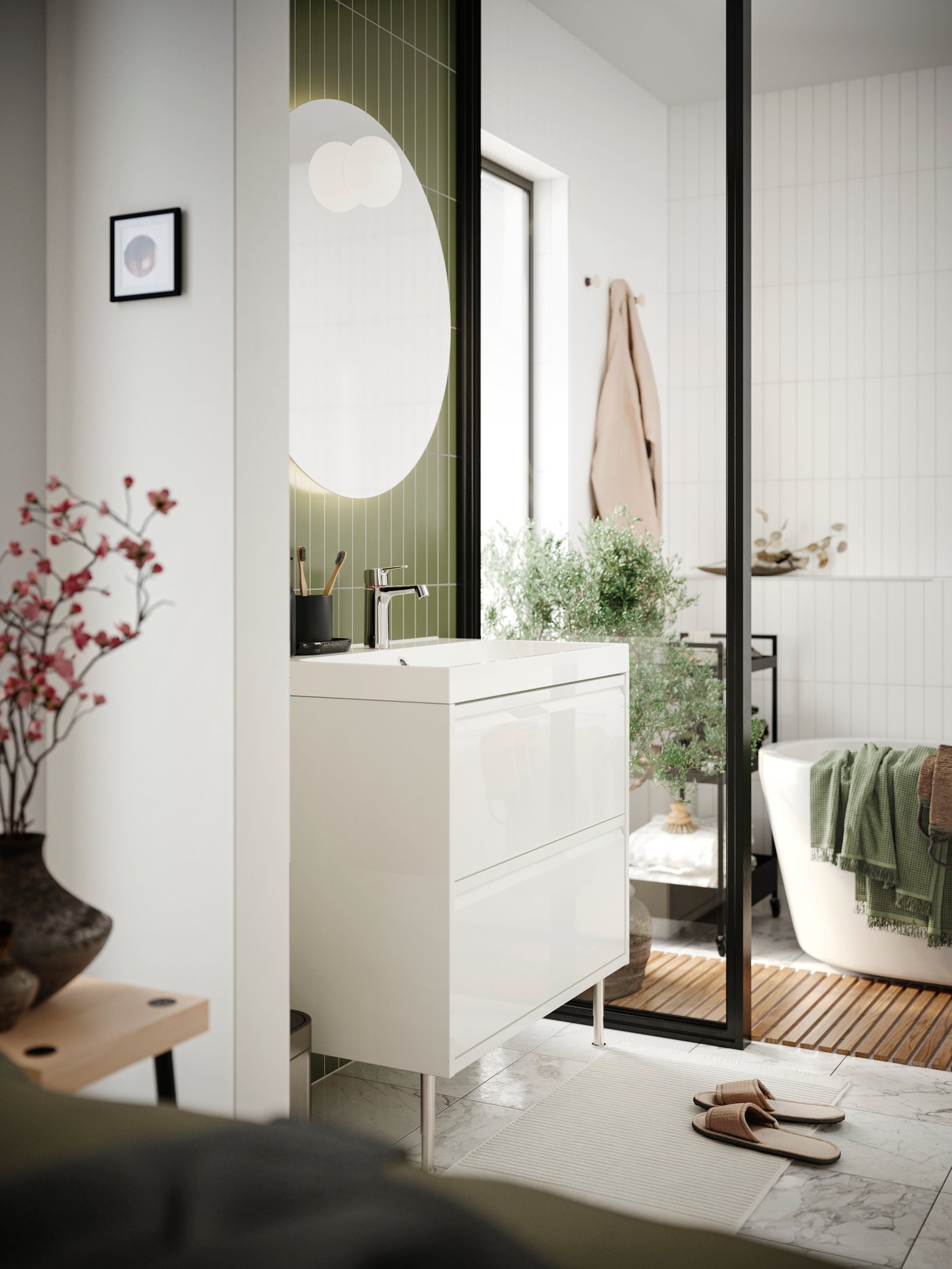 Une salle de bains équipée d'un meuble sous-lavabo IKEA ÄNGSJÖN blanc avec poignées intégrées, derrière lequel se trouvent une baignoire et une petite étagère de salle de bains à roulettes