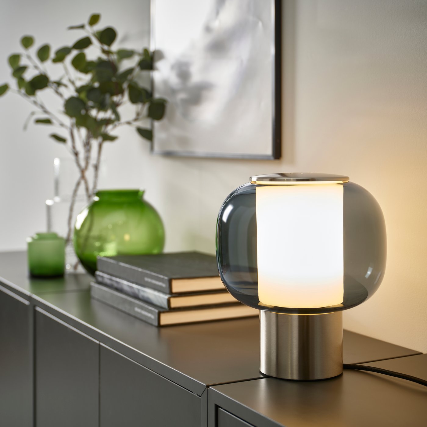 A nickel-plated/grey glass HÖGVIND table lamp in the living room