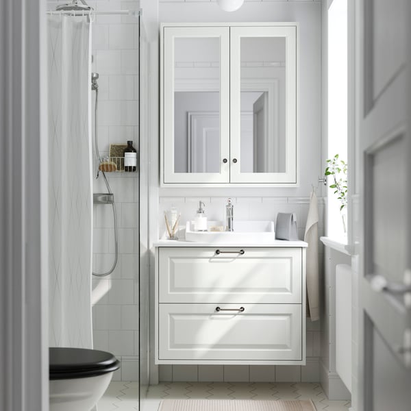 A white bathroom featuring a TÄNNFORSEN wash-stand with drawers and RUTSJÖN semi-recessed wash-basin under a mirror cabinet.
