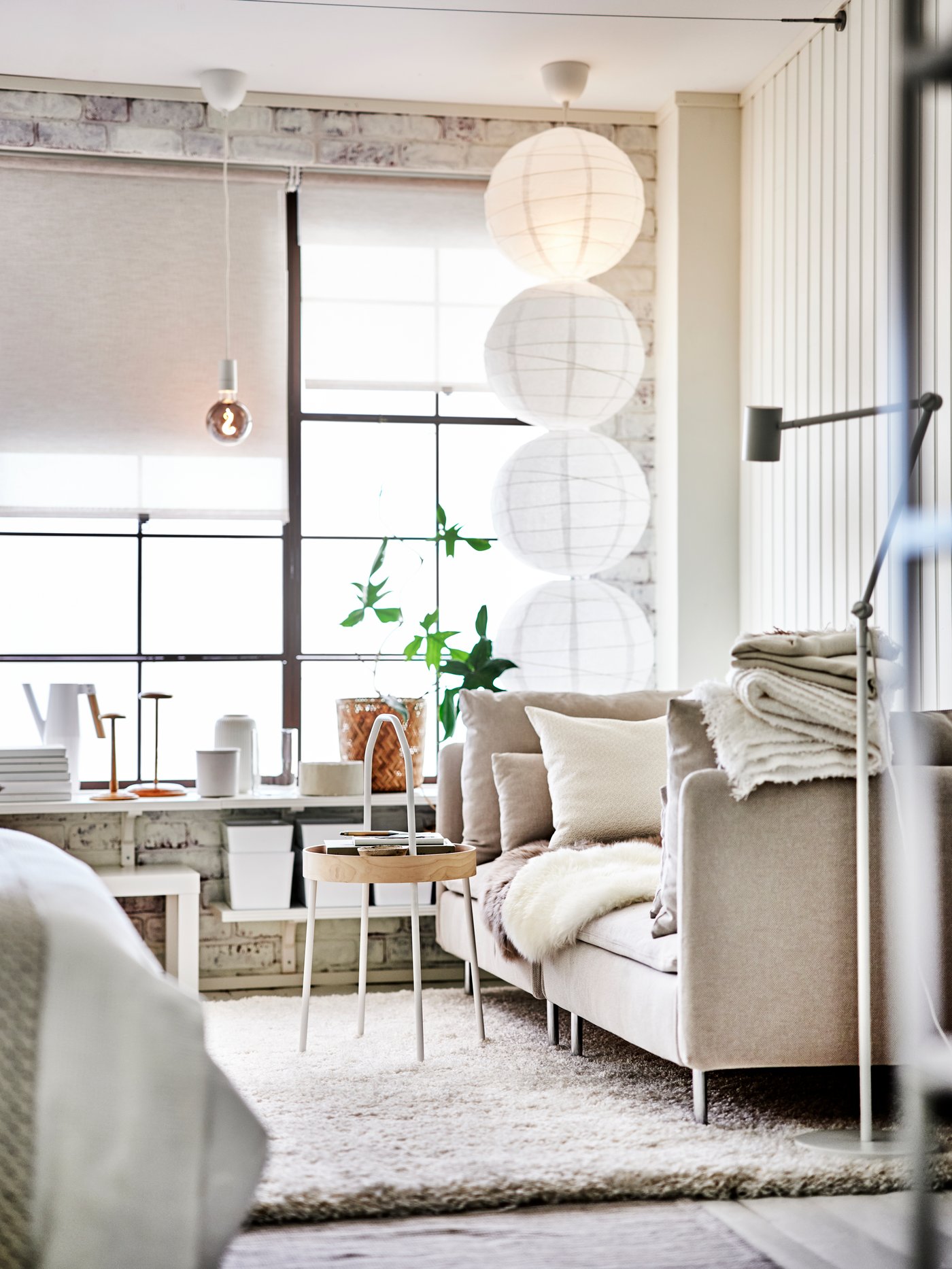 Un living en tonos beige y blancos con un sofá de dos cuerpos frente a una mesa BURVIK. En los ventanales cortinas roller beige SANDVEDEL.