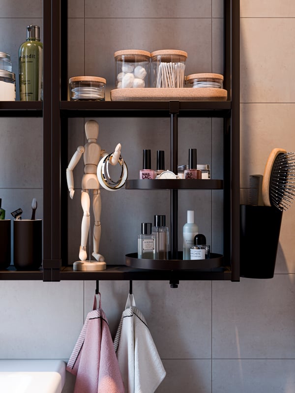 A black wall frame with shelves, a round swivel tray, a container with brushes, an artist’s dummy and hooks with towels.