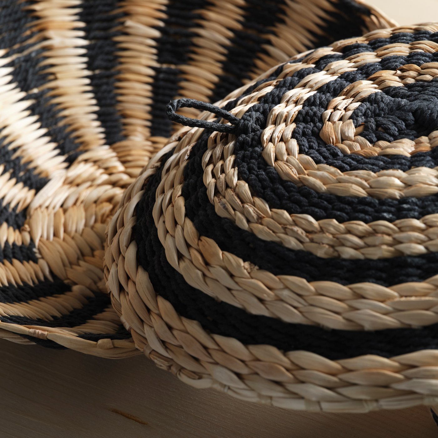 The MÄVINN wall decoration made with banana bark fibres and black cotton thread. It has a black loop on the back for hanging.