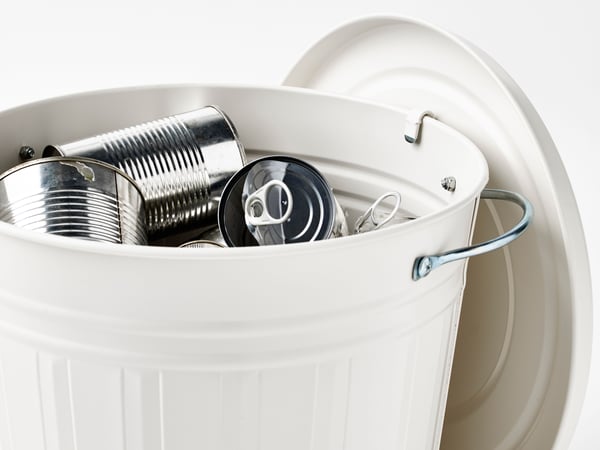 En la imagen puede verse un contenedor de basura blanco lleno de latas vacías. Varias latas no tienen etiquetas, y una de ellas tiene una tapa con anilla. Esta imagen podría guardar relación con el reciclaje, el manejo de residuos o los problemas medioambientales.
