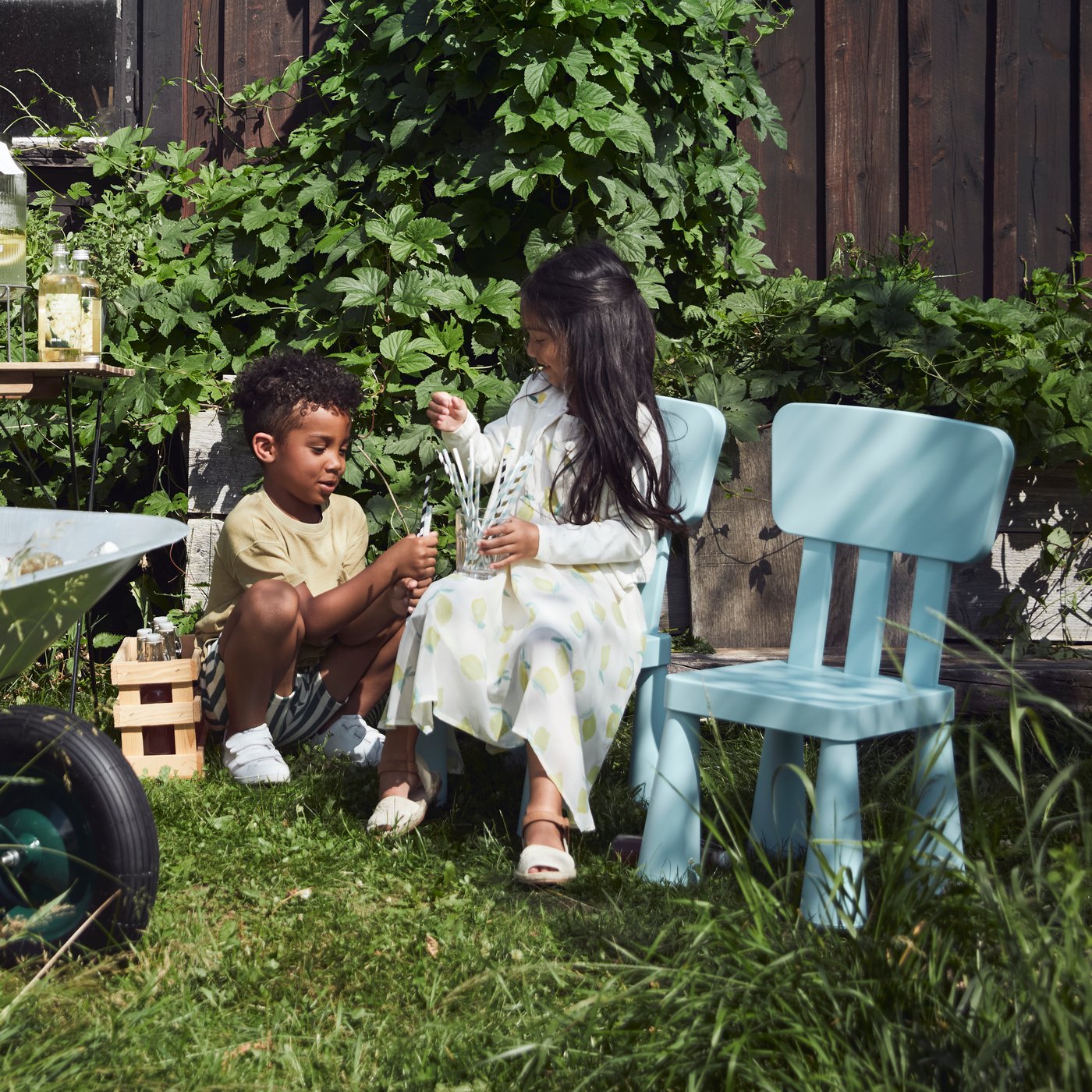 Two children are sitting in the garden, chatting. One of them is sitting on a MAMMUT chair.