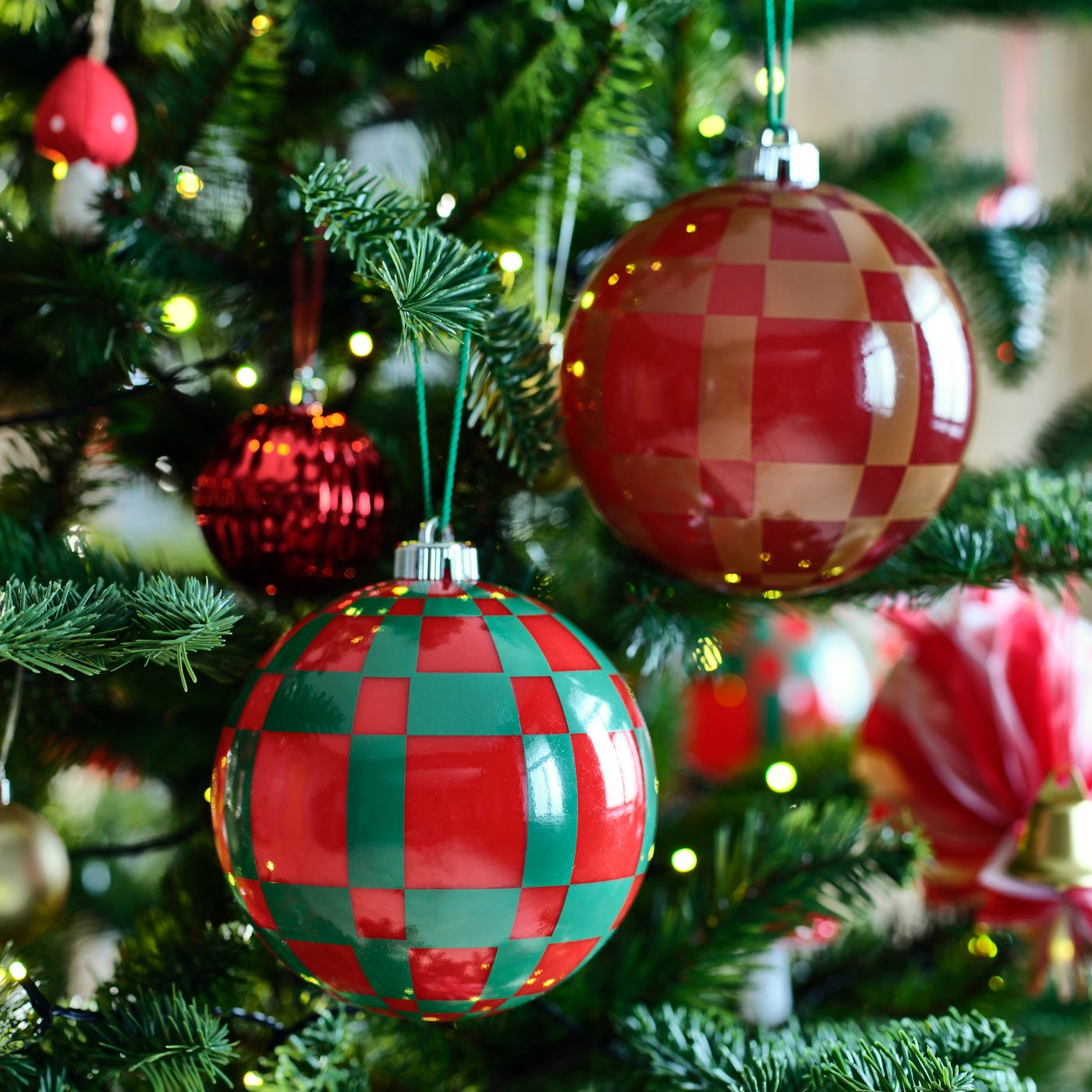 VINTERFINT tree ornaments with a bold checkered pattern adorn the branches of a festive Christmas tree.