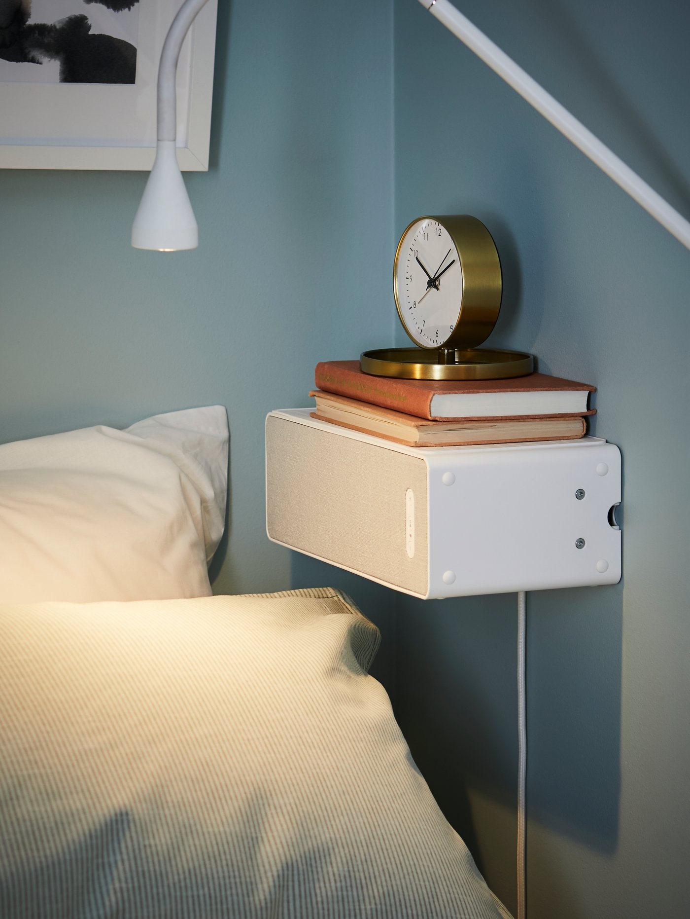 On a TROTTEN desk is a VAPPEBY Bluetooth speaker lamp and NORDMÄRKE wireless phone charger stand.