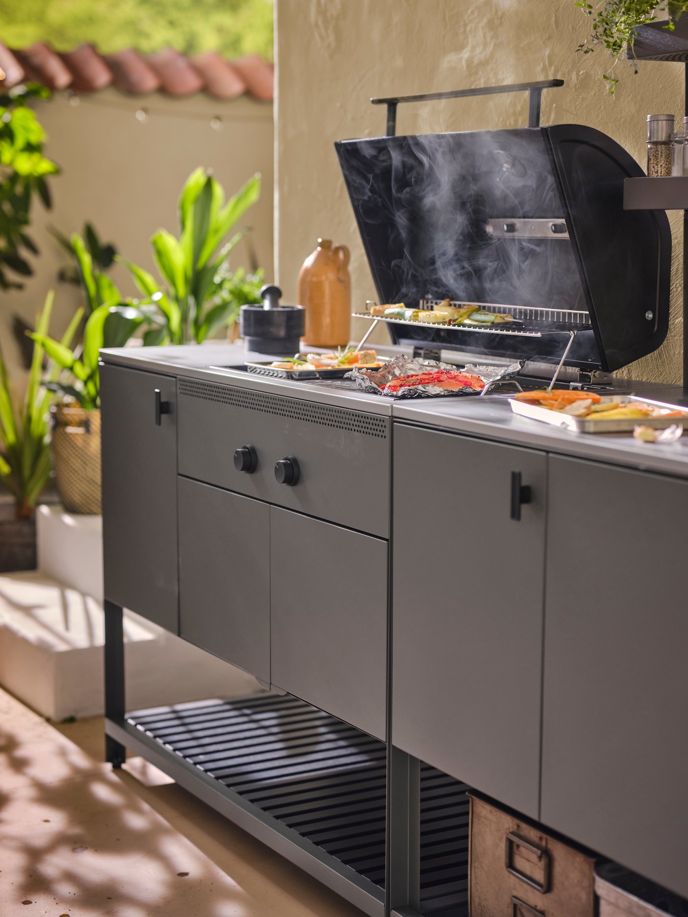 An outdoor BÅTSKÄR charcoal barbecue with an open lid.