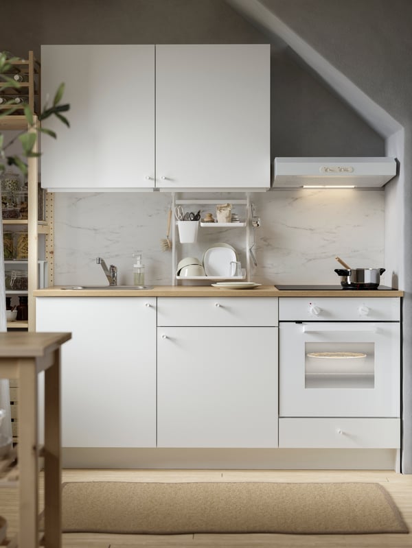 An eclectic kitchen with red and white chequered floors, yellow walls and KNOXHULT base and wall cabinets in white.