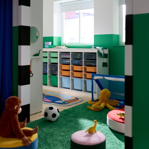 Ein Kinderzimmer mit grün-weiß gestrichenen Wänden und einem TROFAST-System mit Boxen in verschiedenen Größen und Farben.