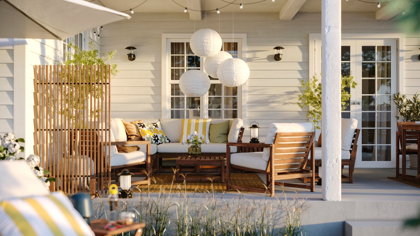 An outdoor space with a NÄMMARÖ 4-seat conversation set, some cushions and several SOLVINDEN LED solar-powered pendant lamps.