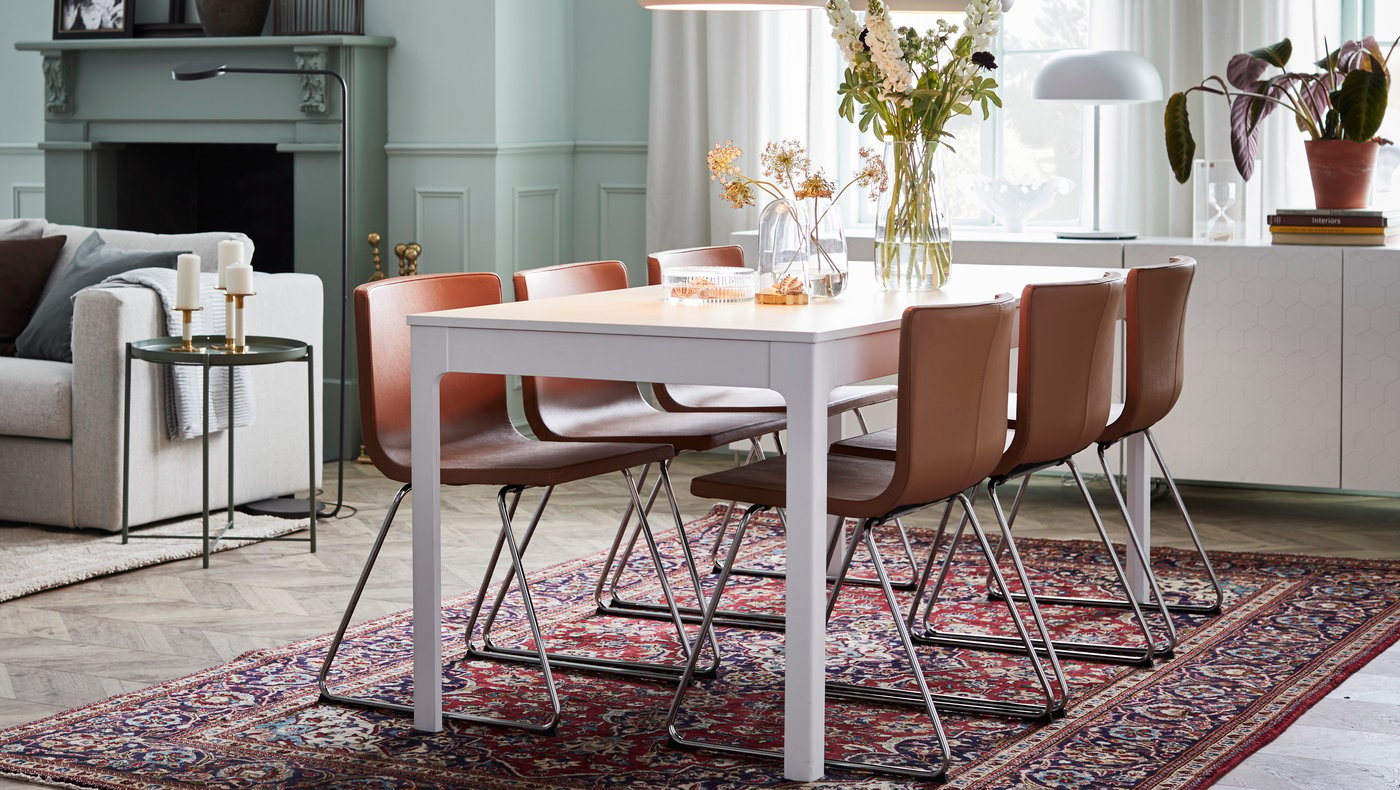 Un comedor con una mesa EKEDALEN blanca de forma rectangular con sillas curvas de color café.
