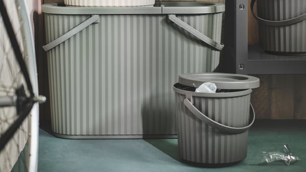 A grey-green DAMMÄNG bin with lid in the garage