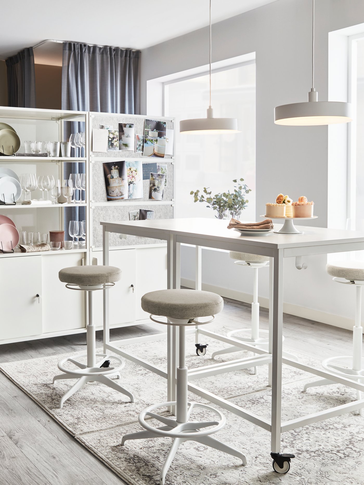 A light room with two side-by-side, white TROTTEN tables, framed by LIDKULLEN sit-stand supports and two TROTTEN cabinets.