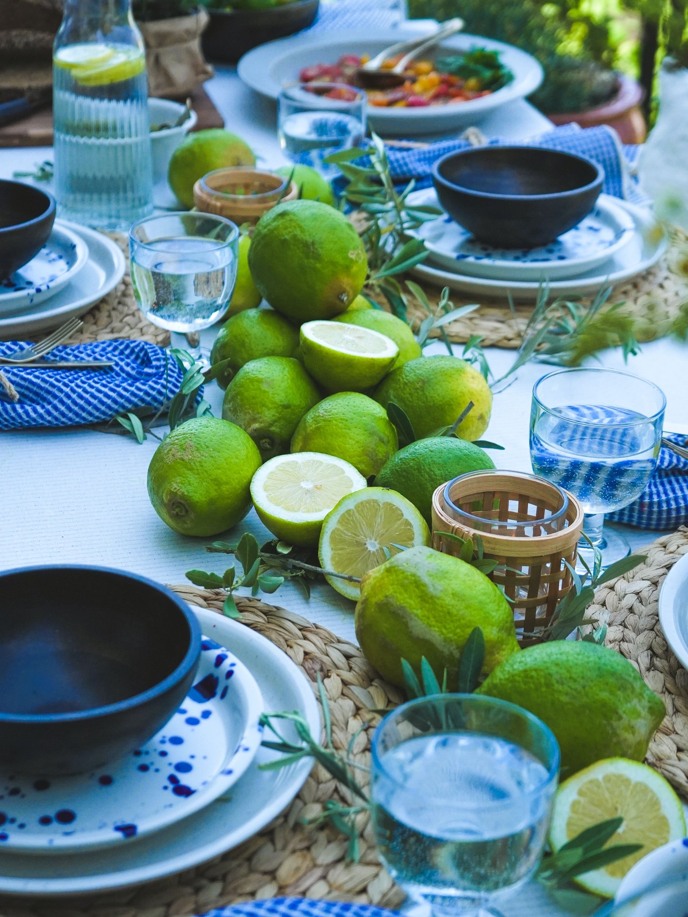 Mediterran gedeckter Tisch mit IKEA Silvereda Tellern, NATTKLOT Besteck, FRUKTDUVA Kelchgläsern, PÅVEFINK Teelichthalter, Limetten, Oliven und Wasserkaraffe.