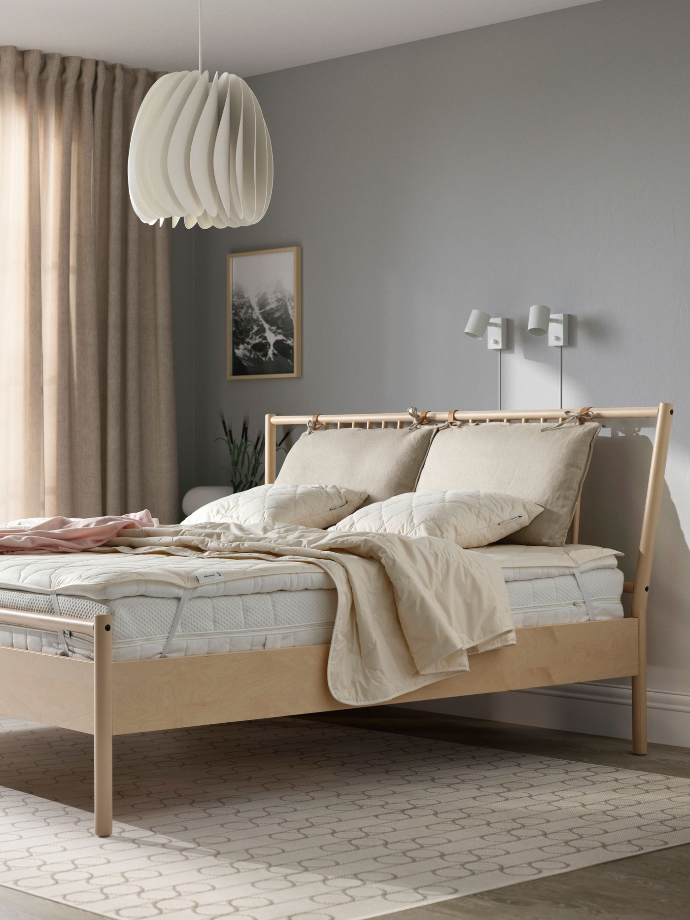 RÅDHUSVIN, un piumino leggermente riscaldante in 100% fibre naturali, giace su un letto marrone con materasso bianco.