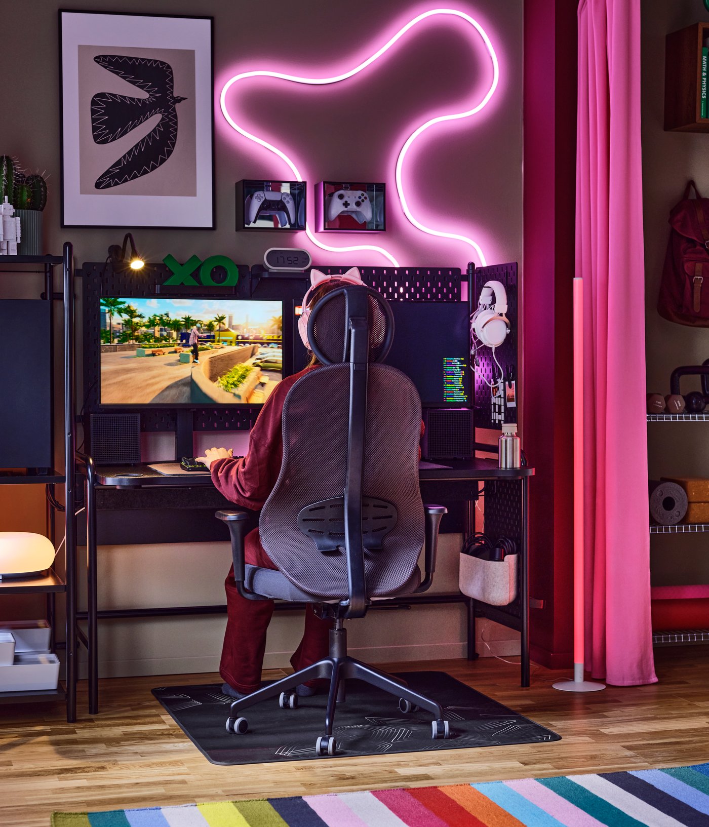 A colourful room with a gaming setup with an anthracite-and-black UTKLASSNING gaming chair and a black FRÖSKELÅS gaming desk.