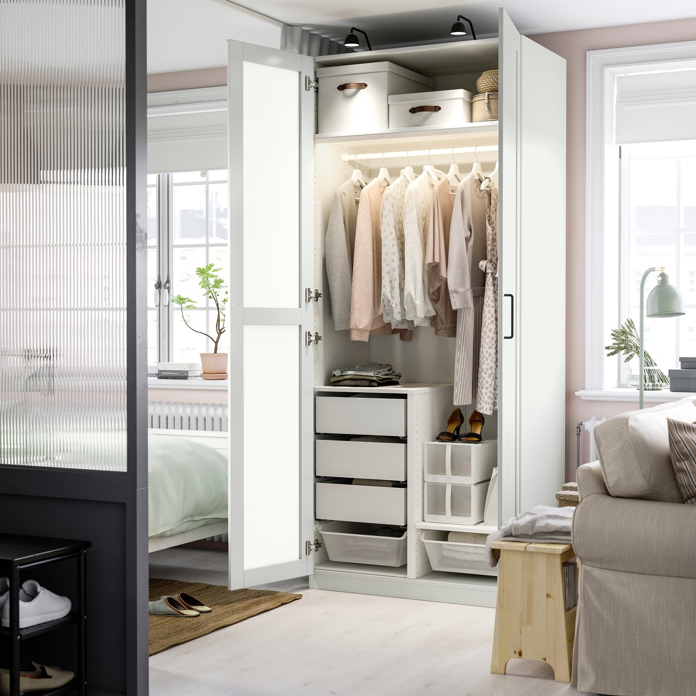 Clóset blanco PAX con ropa en su interior y puertas abiertas.