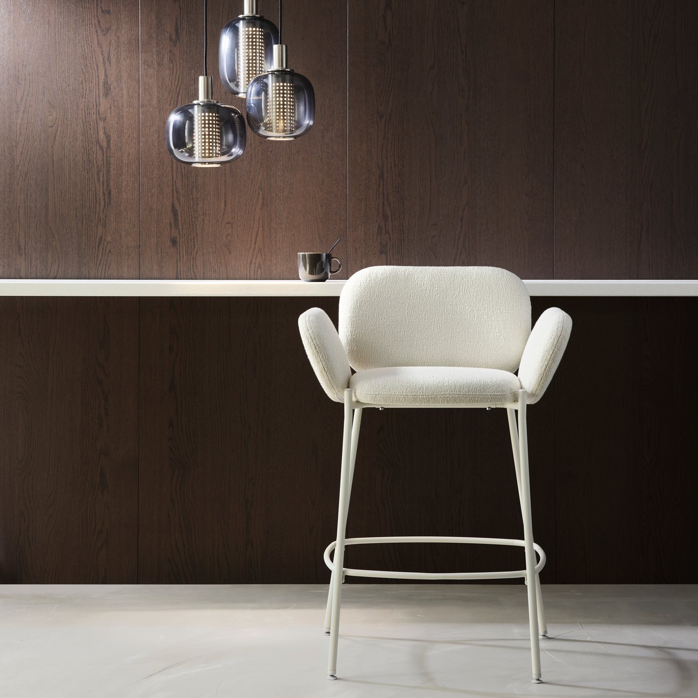 A white/off-white SYNTORP bar stool with backrest stands in a room with a HÖGVIND pendant lamp with 3 lamps.