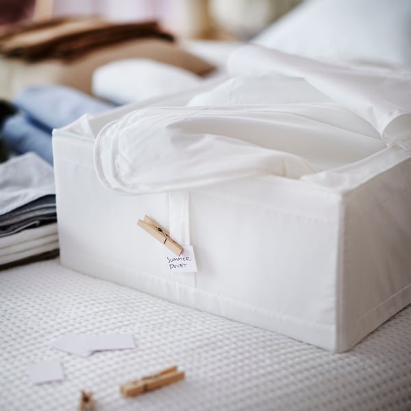 IKEA SKUBB white storage box holding white bed textiles on top of a white bed covered in a white VARELD bedspread.