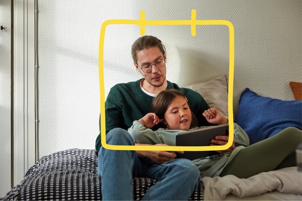 A man and child are looking at a tablet on the couch