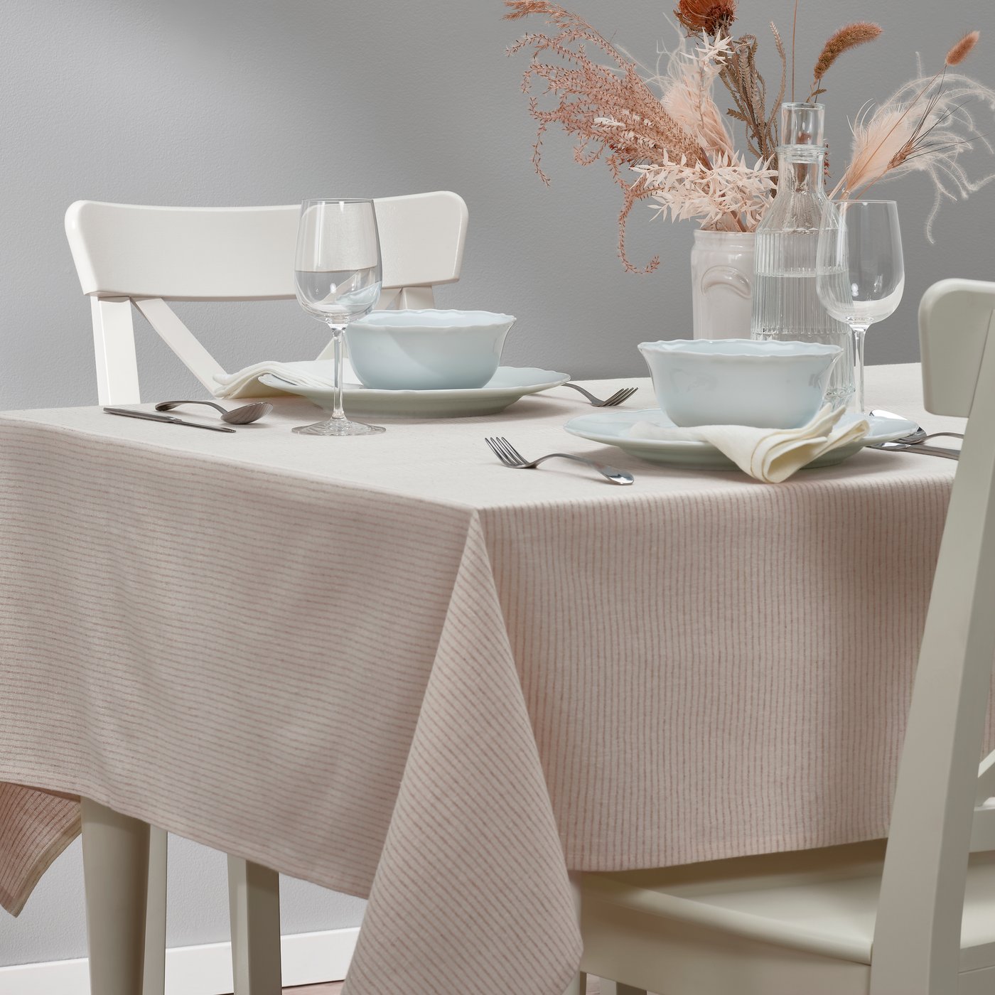 A beige SILVERARV tablecloth set with crockery, glassware and cutlery.