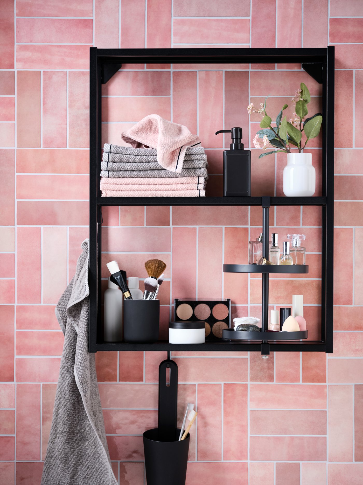 Tiled wall section with a black ENHET shelf-and-swivel-shelf combination, holding VIKFJÄRD towels and make-up accessories.