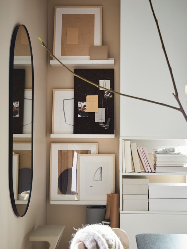 Un angle de la chambre à coucher avec un miroir et des étagères pour photos avec panneau mémo SVENSÅS et tableaux encadrés.