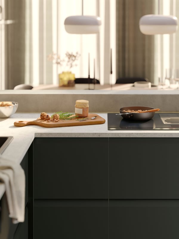A kitchen with UPPLÖV anthracite fronts, FÖRNEBO induction hob with integrated extractor, VARDAGEN carbon-steel frying pan.