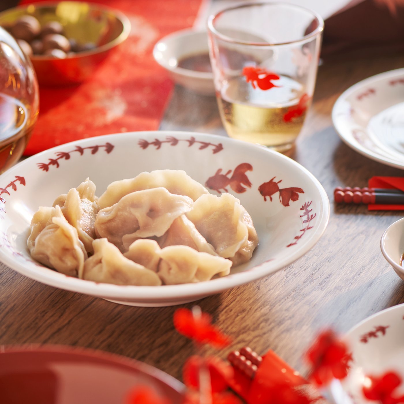 A close-up of a FÖSSTA bowl filled with dumplings that sits on a table among festive tableware.