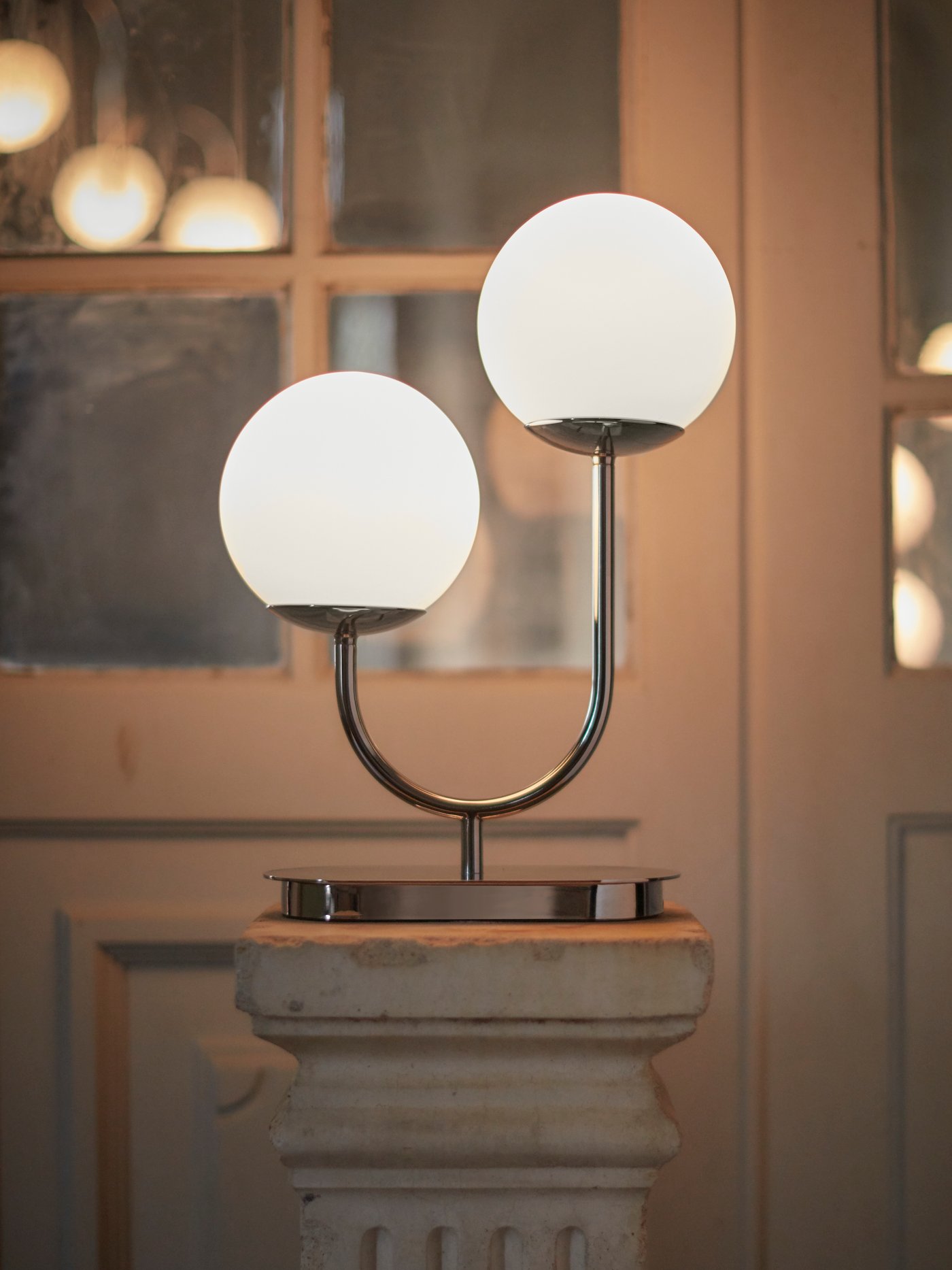Modern bordslampa med två runda glaskupor på piedestal.