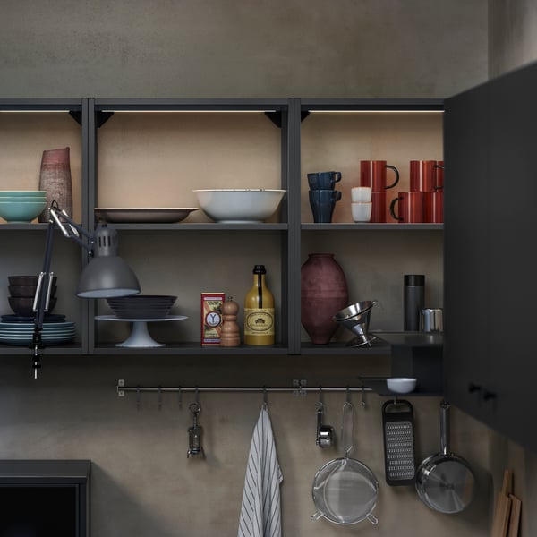ENHET wall frame with shelves in anthracite with bowls, cups, and cooking essentials against a textured wall.