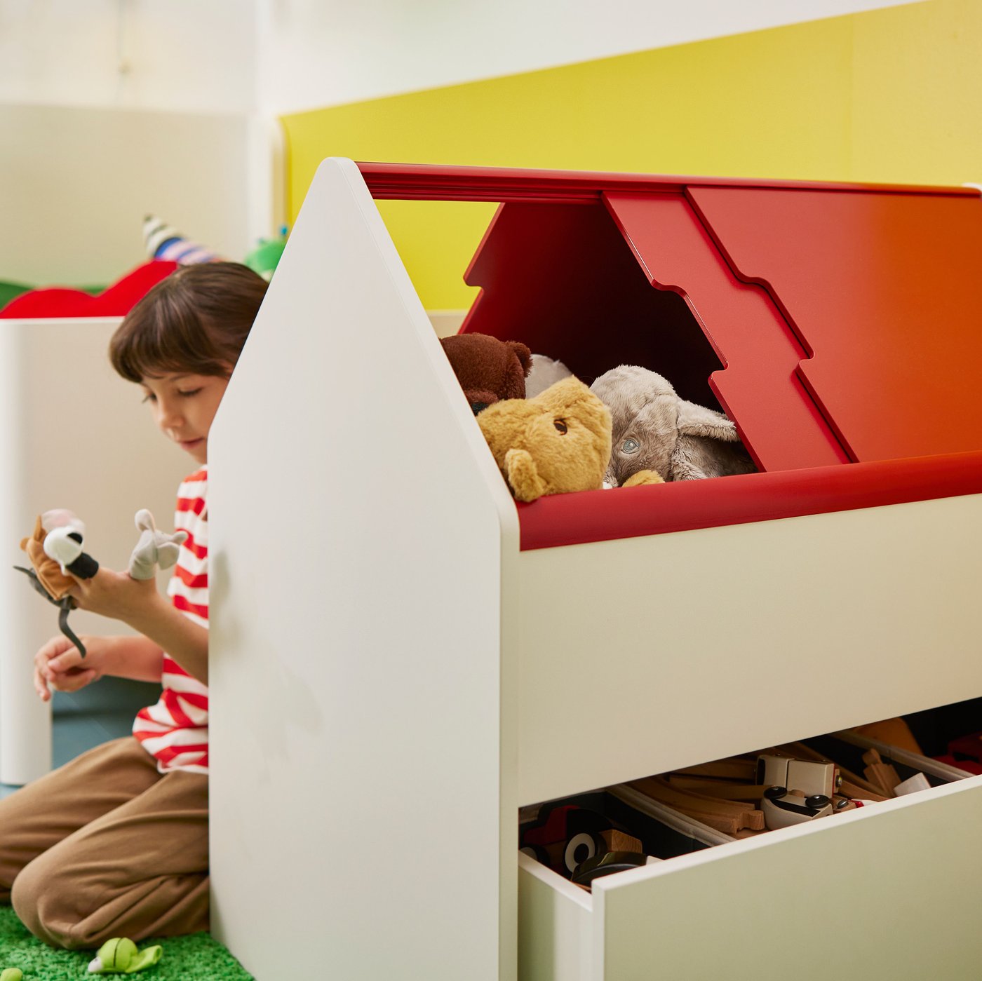 Girl playing with soft toys, sitting behind VITBJÖRN storage unit with drawer full of toys. BUSUNGE extendable bed in back.