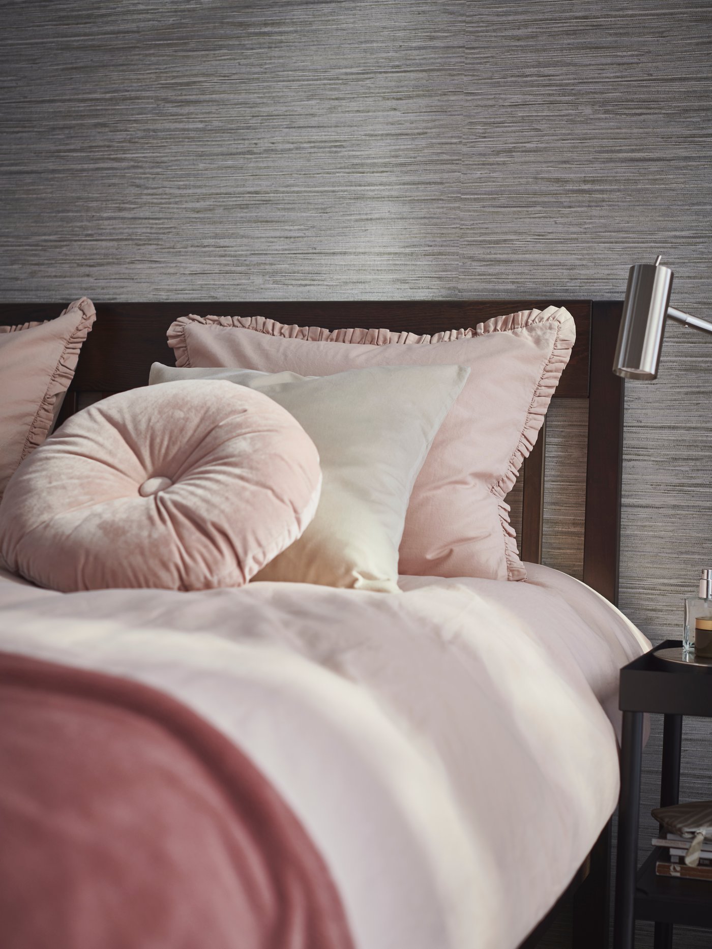 In a bedroom, a KRANSBORRE cushion, SANELA cushion cover and pink KRANSKRAGE quilt cover set are on a tidy bed.