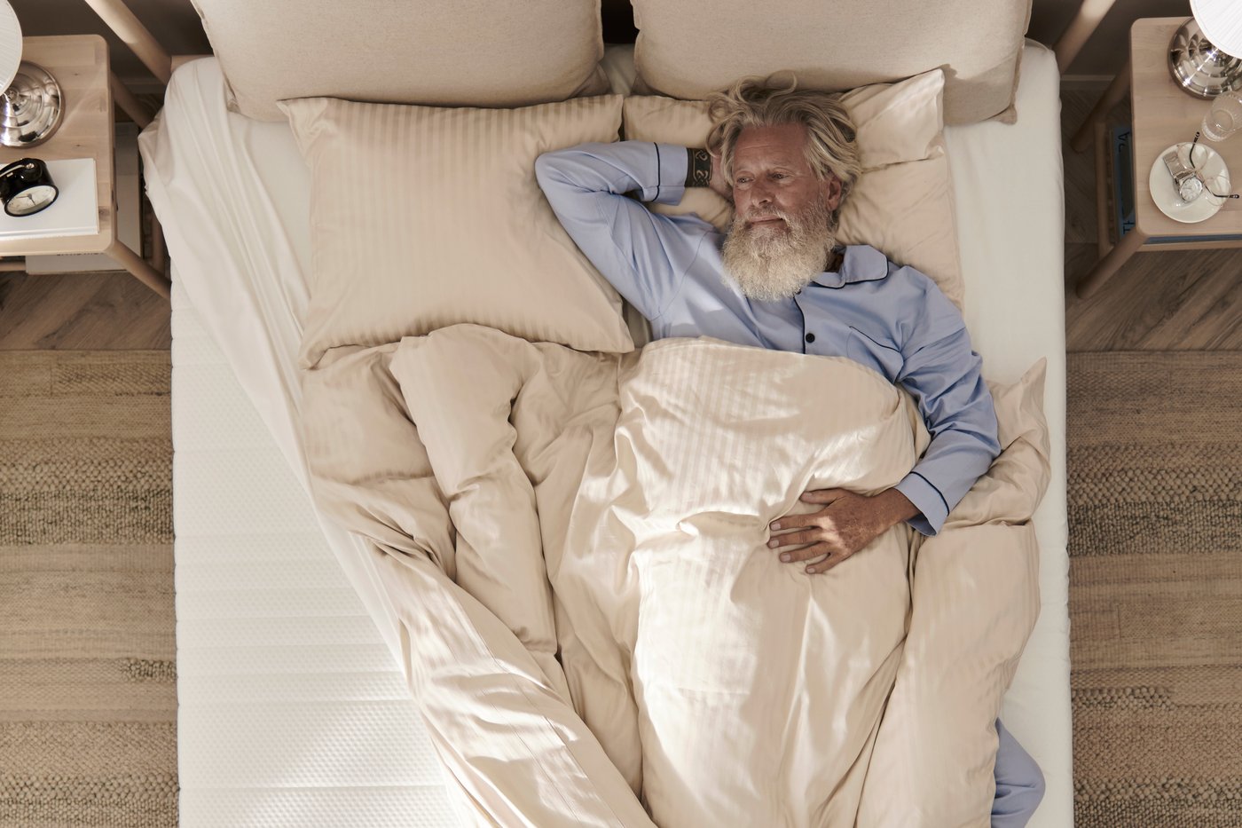 Vue aérienne d’un homme couché sur un matelas blanc avec une NATTJASMIN housse de couette beige clair.