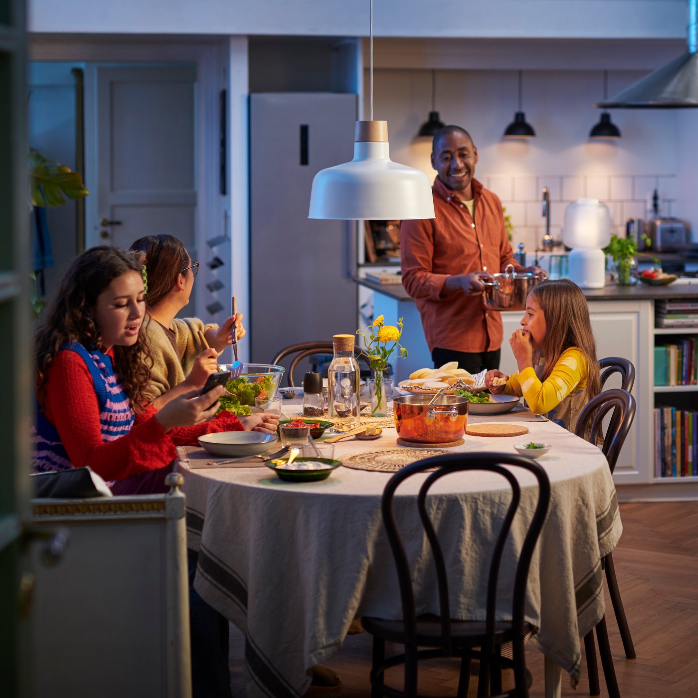 A family is sitting around a dining table with a white/smart STARKVIND air purifier in the background.