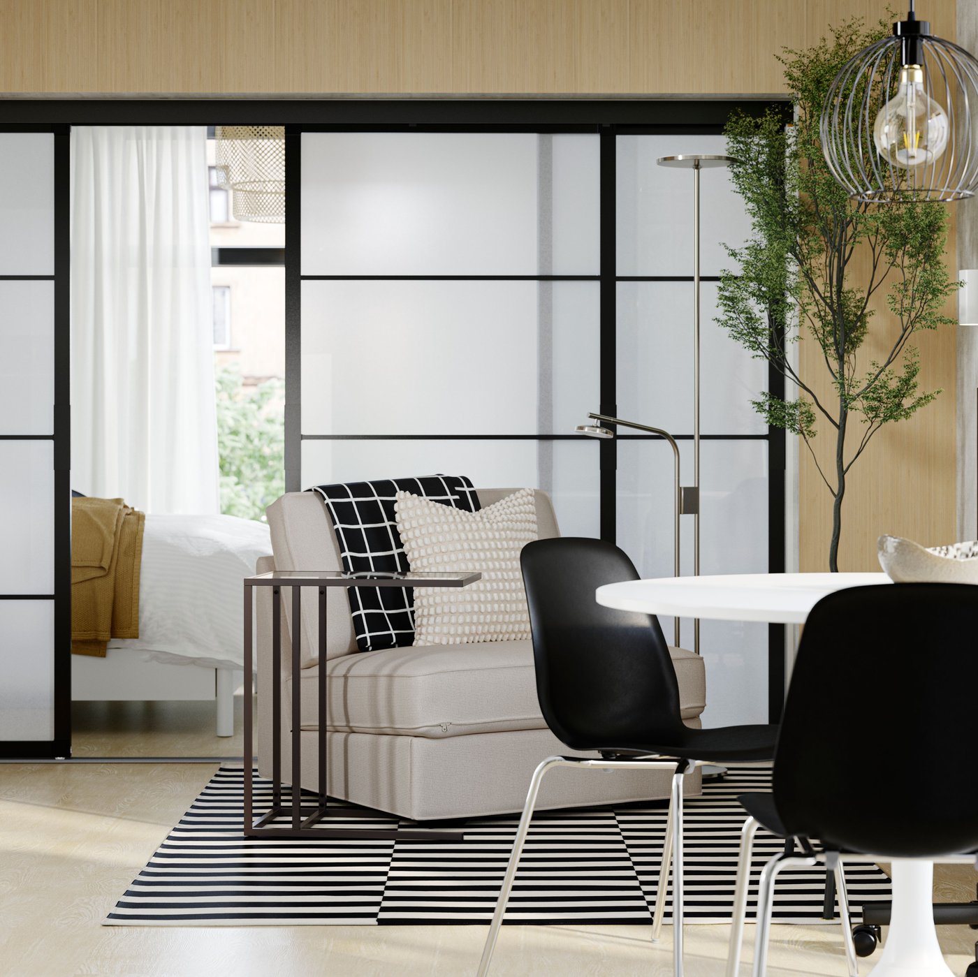 The open area of a minimalistic apartment has a dining table, chairs and armchair in front of SKYTTA sliding doors.