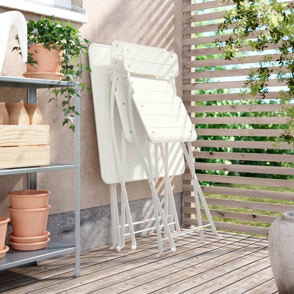 An outdoor off-white/off-white SUNDSÖ table and 2 folding chairs outside