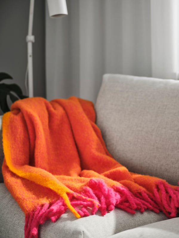 IKEA KLIPPOXEL orange/bright pink KLIPPOXEL throw on a sofa.